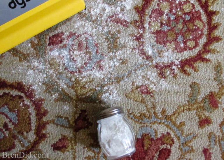 Carpet deodorizer powder spread on carpet next to vacuum.