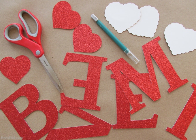 Get ready for Valentine's Day parties and events with this glitter garland inspired by Pottery Barn Kids. This easy Knock Off DIY craft uses glitter cardstock, some twine, and wooden beads to make a charming Valentine's Day banner for under $3.