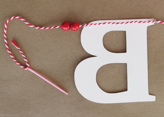 Get ready for Valentine's Day parties and events with this glitter garland inspired by Pottery Barn Kids. This easy Knock Off DIY craft uses glitter cardstock, some twine, and wooden beads to make a charming Valentine's Day banner for under $3.