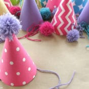 Fabric covered party hats are an easy craft and an affordable way to take your birthday party decor to the next level. With a little patterned fabric, glue, yarn and card stock you can turn a common party decoration into something extraordinary.