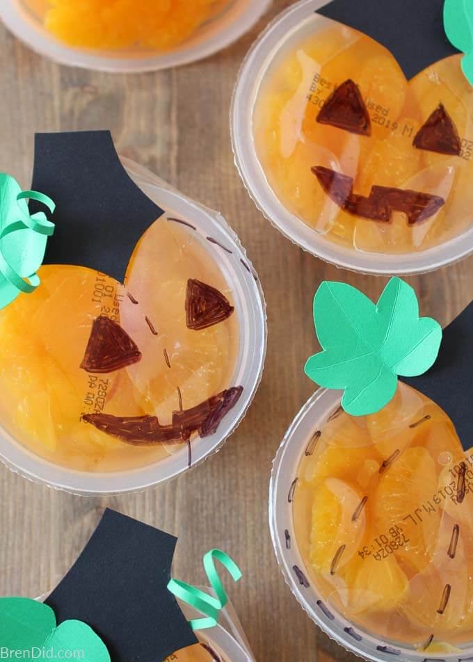 orange Halloween fruit cups decorated to look like jackolanterns