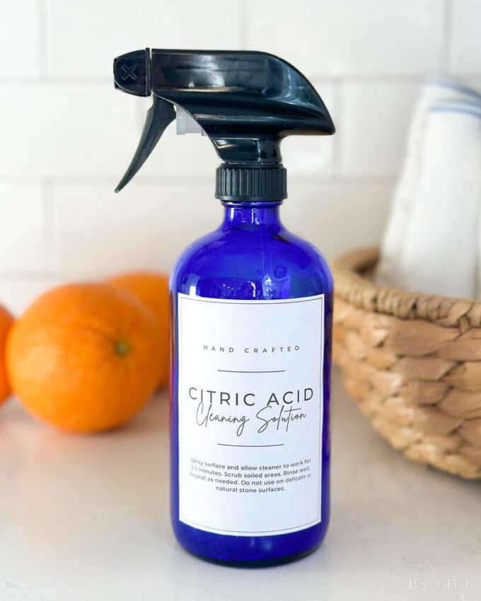 Citric Acid Cleaning Solution in a blue glass spray bottle.