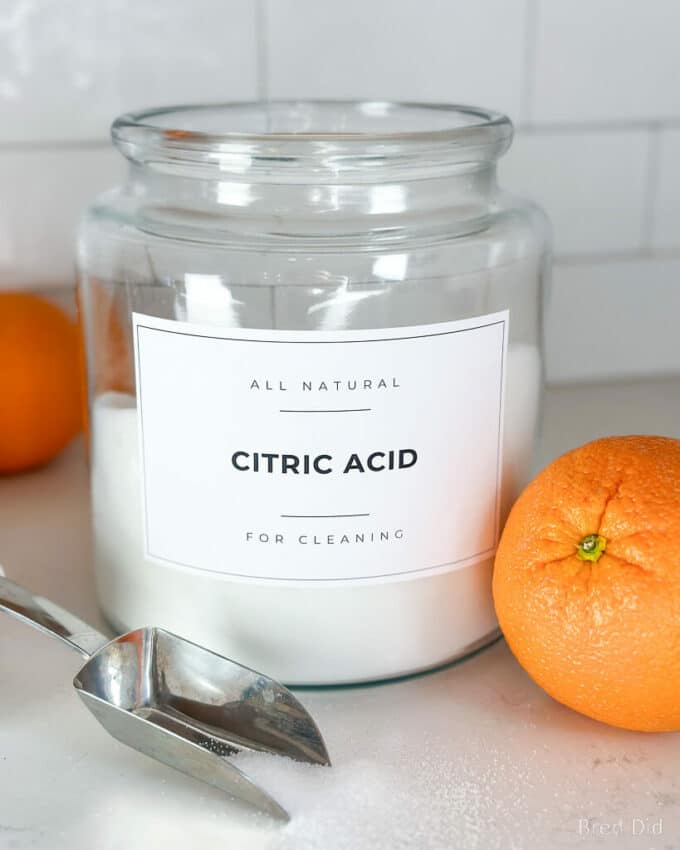 Citric acid for cleaning in a glass storage jar with metal scoop.